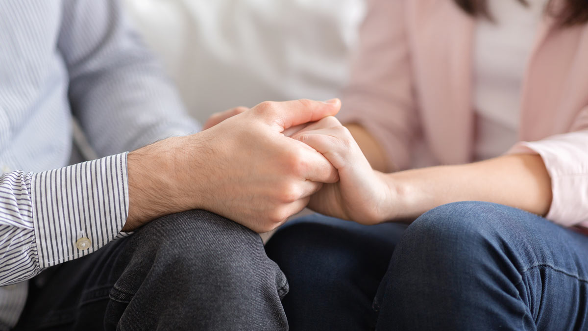 Couple holding hands on couch in therapy. Couples Therapy Before There's a Crisis: The Case for Going When Things Are "Fine"